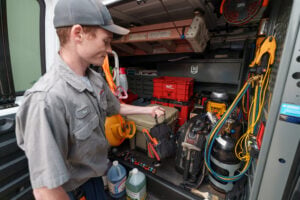 A Bass Air Conditioning Co. Technician retrieving tools from truck - Bass Air Conditioning Co. A Bass Air Conditioning Co. Technician retrieving tools from truck