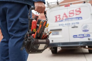 Bass Air Conditioning Co technician carrying tools to truck - Bass Air Conditioning Co. A Bass Air Conditioning Co. technician carrying tools to a Bass Air Conditioning Co. truck.